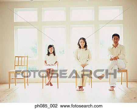 Stock Image - Father, mother and daughter sitting on chairs. Fotosearch