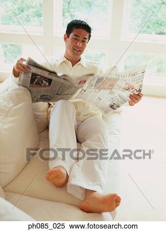 Man reading newspaper on sofa View Large Photo Image Stock Photography - Man reading newspaper on sofa. Fotosearch