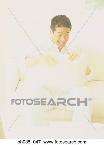 Man sitting on sofa, smiling View Large Photo Image Stock Photo - Man sitting on sofa, smiling. Fotosearch