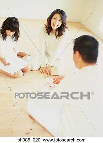 Stock Image - Parents and daughter playing cards. Fotosearch