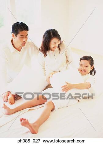 Stock Photo - Parents and daughter playing on sofa. Fotosearch