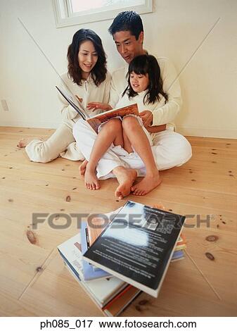 Stock Photo - Parents and daughter reading a book. Fotosearch