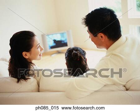 Parents and daughter watching television, rear view View Large Photo Image Stock Photography - Parents and daughter watching television, rear view. Fotosearch