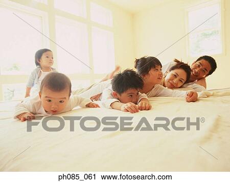 Portrait of a happy family lying on bed View Large Photo Image Stock Image - Portrait of a happy family lying on bed. Fotosearch