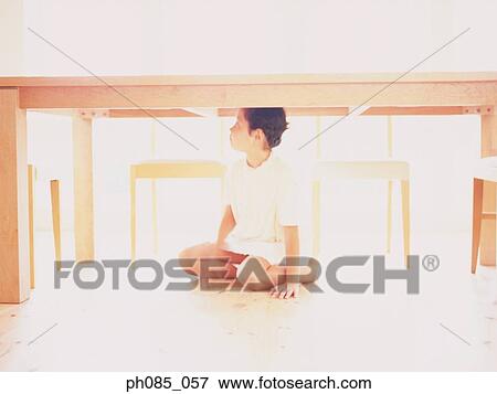 Young girl sitting under a table View Large Photo Image Stock Photo - Young girl sitting under a table. Fotosearch