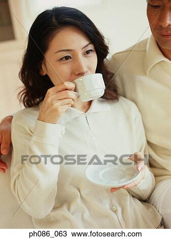 Asian couple, woman drinking coffee View Large Photo Image Stock Image - Asian couple, woman drinking coffee. Fotosearch