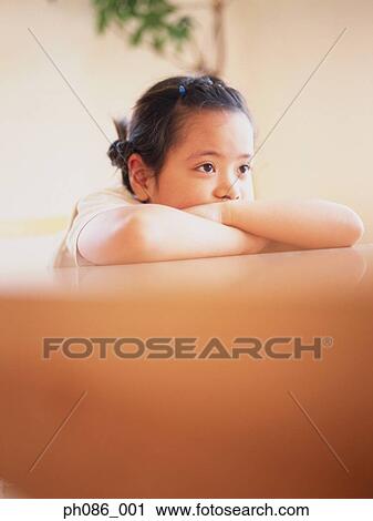 Stock Image - Daydreaming girl leaning on couch . Fotosearch