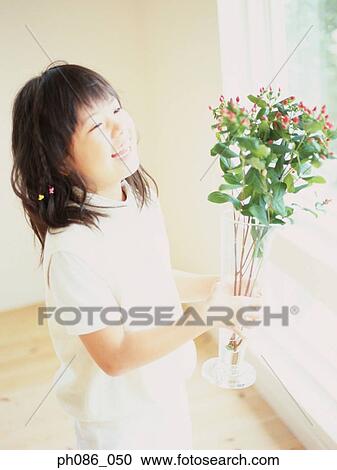 Stock Image - Girl holding a vase of flowers. Fotosearch