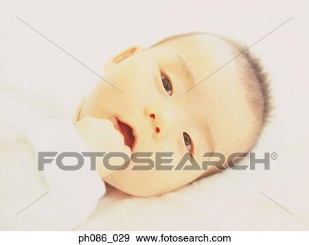 Infant lying on bed, close-up View Large Photo Image Stock Photo - Infant lying on bed, close-up. Fotosearch