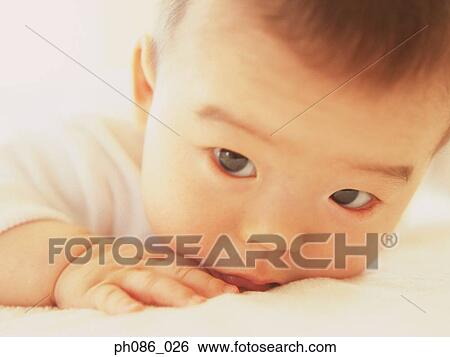 Infant lying on bed, close-up View Large Photo Image Stock Photograph - Infant lying on bed, close-up. Fotosearch