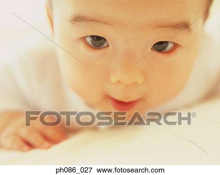 Stock Photo - Infant lying on bed smiling, close-up. Fotosearch