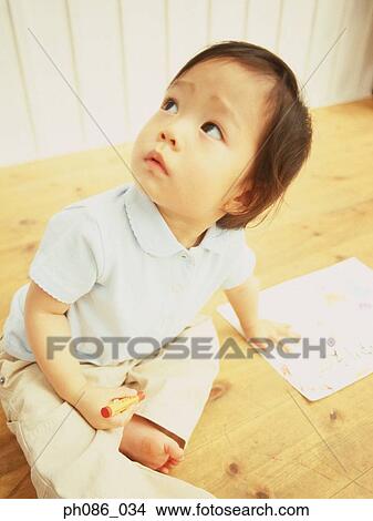 Picture - Little girl looking up, holding a crayon. Fotosearch