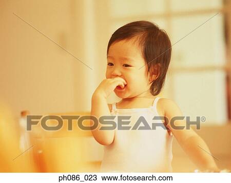 Little girl puts her fingers in her mouth View Large Photo Image Stock Image - Little girl puts her fingers in her mouth. Fotosearch