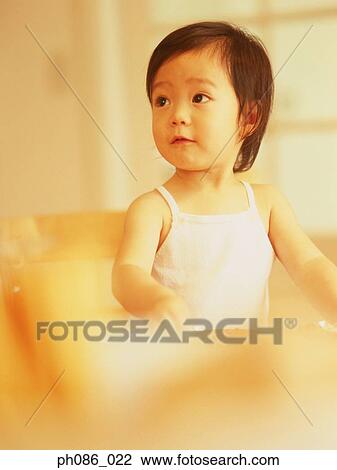 Stock Image - Little girl sitting, looking away. Fotosearch