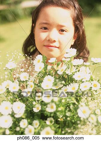 Stock Photography - Young girl standing behind flowers. Fotosearch