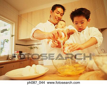 Boy cracking egg over bowl, father with a baby helping View Large Photo Image Picture - Boy cracking egg over bowl, father with a baby helping. Fotosearch
