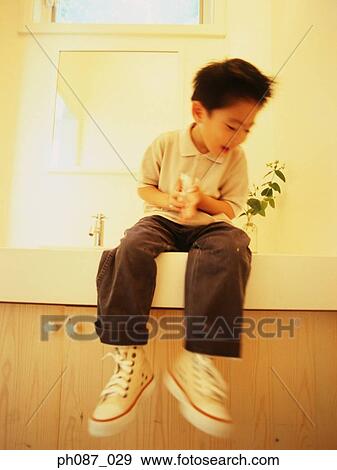 Boy sitting on cabinet View Large Photo Image Stock Photo - Boy sitting on cabinet. Fotosearch