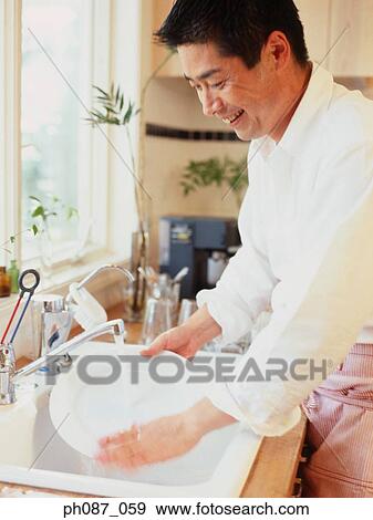 Stock Photo - Man washing a white plate. Fotosearch