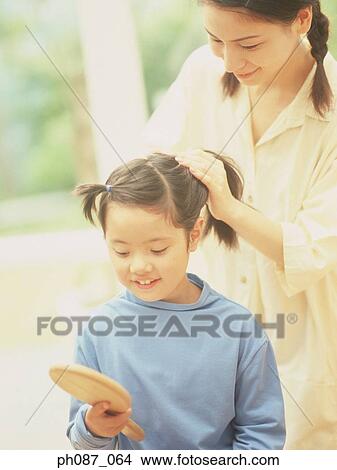 Mother fixing daughter's hair View Large Photo Image Picture - Mother fixing daughter's hair . Fotosearch
