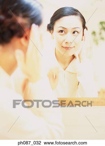 Woman looking at herself in the mirror View Large Photo Image Stock Image - Woman looking at herself in the mirror. Fotosearch