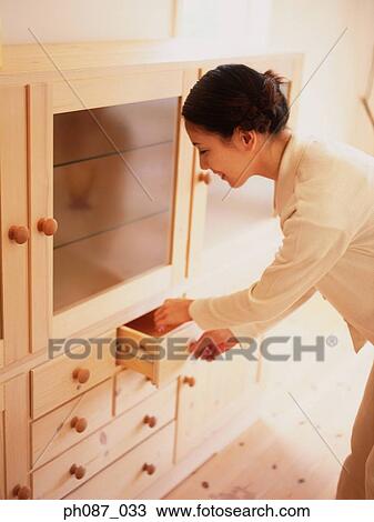 Stock Image - Woman pulling drawer. Fotosearch