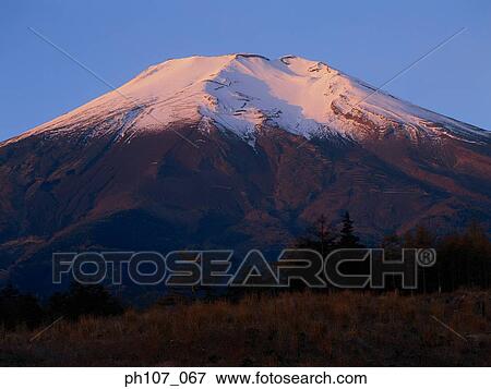 Stock Photo - Orange sunset light reflects on peak of Mt. Fuji, Japan. Fotosearch