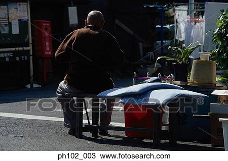 Stock Image - Matured Japanese man sitting on a bench, rear view. Fotosearch