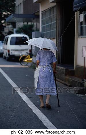 Stock Image - Woman with walking stick, rear view. Fotosearch