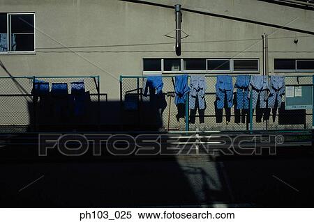 Stock Photography - Uniforms hanging on fence. Fotosearch