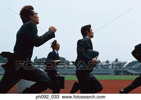 Stock Image - Businessmen running on stadium track, carrying briefcases. Fotosearch