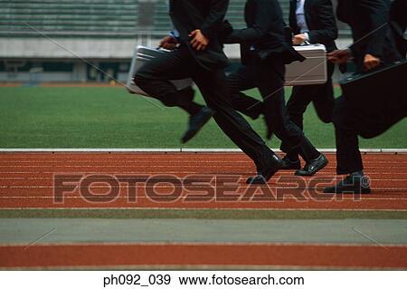 Businessmen running on stadium track, carrying briefcases, low section View Large Photo Image Stock Photo - Businessmen running on stadium track, carrying briefcases, low section. Fotosearch