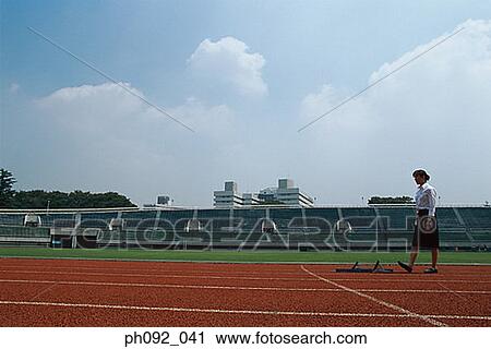 Stock Image - Businesswoman walking towards starting block . Fotosearch