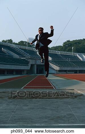 Picture - Businessman long jumping in mid-air. Fotosearch
