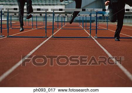 Businessmen leaping hurdle, low section View Large Photo Image Stock Photo - Businessmen leaping hurdle, low section. Fotosearch