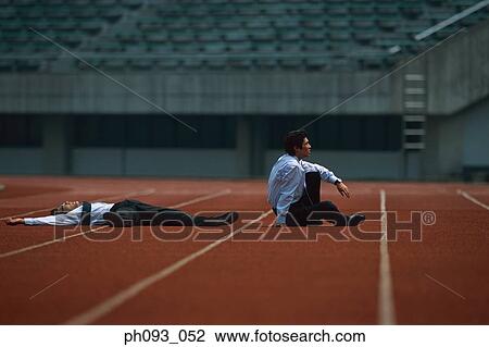 Stock Image - Businessmen lying on track after defeat. Fotosearch
