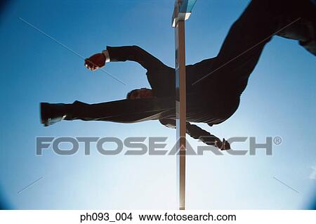 Silhouette of businessman leaping hurdle, low angle view View Large Photo Image Picture - Silhouette of businessman leaping hurdle, low angle view . Fotosearch