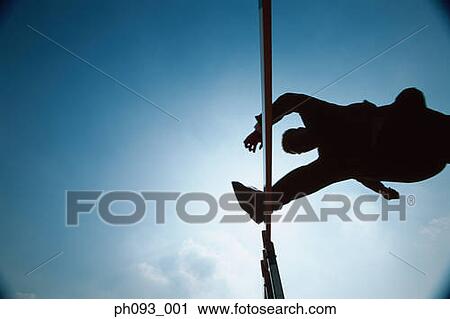 Stock Image - Silhouette of businessman leaping hurdle, low angle view . Fotosearch