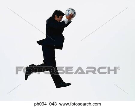 Young businessman leaping in air, holding a soccer ball View Large Photo Image Stock Image - Young businessman leaping in air, holding a soccer ball. Fotosearch