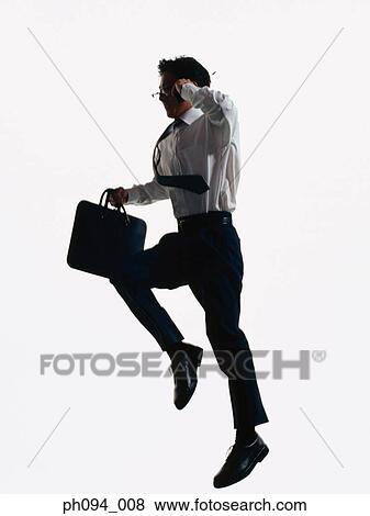 Stock Photo - Young businessman leaping in air, holding cell phone and briefcase. Fotosearch