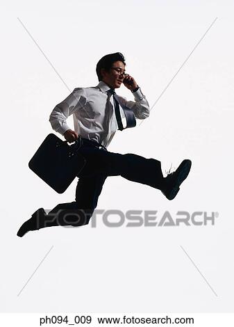 Young businessman leaping in air, holding cell phone and briefcase View Large Photo Image Stock Photo - Young businessman leaping in air, holding cell phone and briefcase. Fotosearch