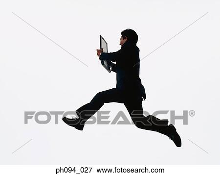 Young businessman leaping in air, holding a computer notebook View Large Photo Image Stock Photo - Young businessman leaping in air, holding a computer notebook. Fotosearch