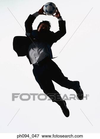 Young businessman leaping in air, holding a soccer ball View Large Photo Image Stock Photo - Young businessman leaping in air, holding a soccer ball. Fotosearch
