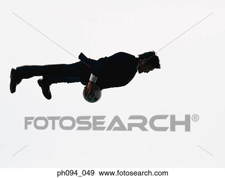 Stock Photo - Young businessman leaping in air, holding a soccer ball. Fotosearch