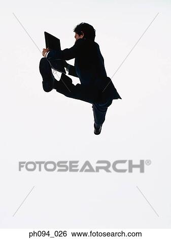 Young businessman leaping in air, holding a computer notebook View Large Photo Image Stock Photograph - Young businessman leaping in air, holding a computer notebook. Fotosearch
