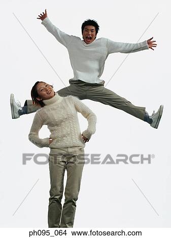 Two young Asian man and woman in pants & sweat-shirts, jumping in mid-air View Large Photo Image Picture - Two young Asian man and woman in pants & sweat-shirts, jumping in mid-air. Fotosearch