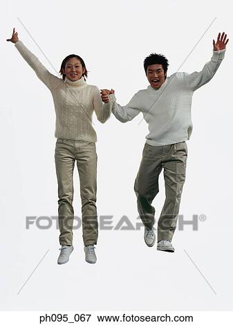 Two young Asian man and woman in pants & sweat-shirts, jumping in mid-air View Large Photo Image Stock Photo - Two young Asian man and woman in pants & sweat-shirts, jumping in mid-air. Fotosearch