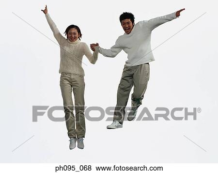 Stock Photo - Two young Asian man and woman in pants & sweat-shirts, jumping in mid-air. Fotosearch