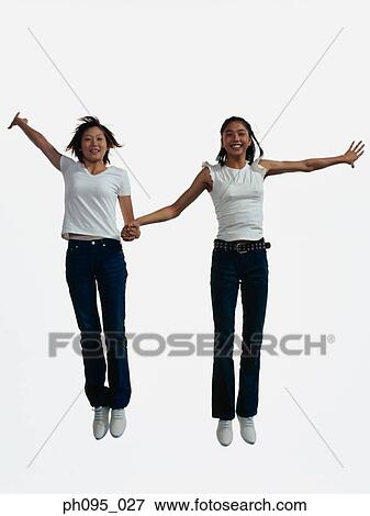Stock Photo - Two young Asian women in jeans & t-shirt, jumping in mid-air. Fotosearch