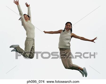 Two young Asian women in pants & sweat-shirts, jumping in mid-air View Large Photo Image Picture - Two young Asian women in pants & sweat-shirts, jumping in mid-air. Fotosearch
