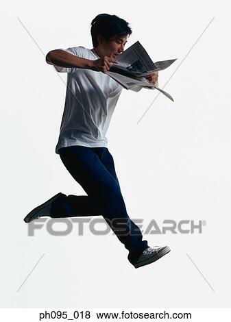 Young Asian man in jeans & t-shirt, and newspaper, jumping in mid-air View Large Photo Image Stock Photo - Young Asian man in jeans & t-shirt, and newspaper, jumping in mid-air. Fotosearch